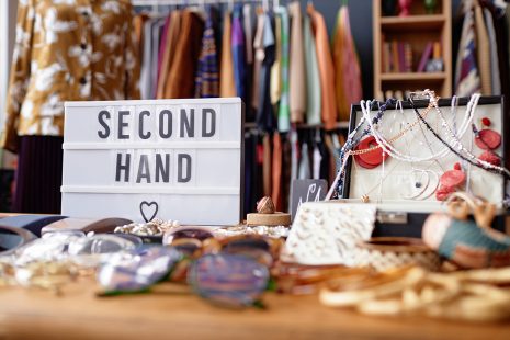 Close up on sign with inscription Second Hand and jewelry case with vintage accessories at thrift store checkout, copy space